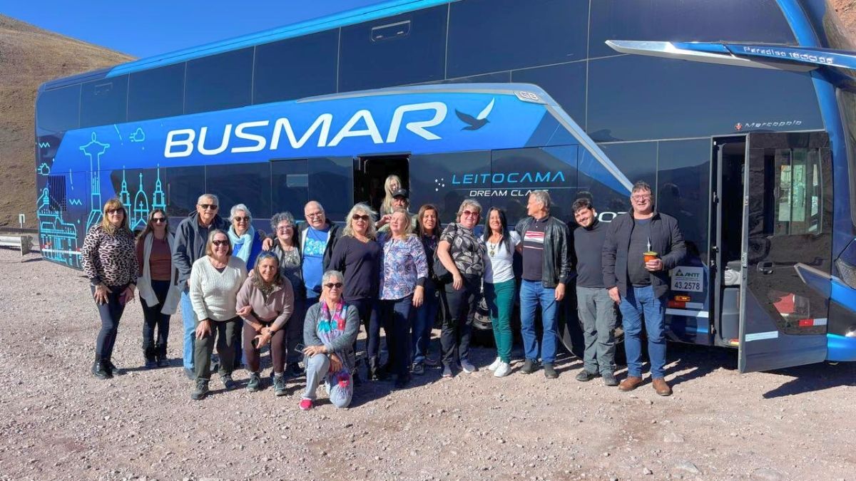 Grupo de viajantes MaxxiTours posando em frente ao ônibus Leito-Cama